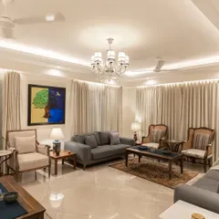 We designed this living room with a tranquil palette of cream and wood. The space is furnished with elegant pieces from Rosabagh, complemented by a large, vibrant painting that adds a pop of color. The overall effect is one of sophisticated calm.