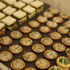A closer look at the savory bites offered at a recent brand event. These mini mushroom tarts and layered finger sandwiches are crafted to be easily enjoyed while standing, making them a perfect choice for corporate mixers and launch parties.