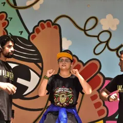 Learning to communicate with our hands and hearts. Three volunteers practice sign language in front of our colorful wall mural, demonstrating a key part of our mission to build bridges with the Deaf community.