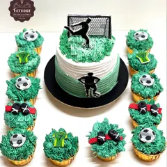 A football theme cake that comes with matching cupcakes. The main cake is a Lotus Biscoff flavour, and the set is decorated with grass-like frosting and football-themed toppers.