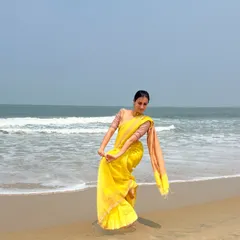 A classic dance pose in a vibrant yellow saree on the beach. This is an example of a dance-inspired modeling pose, where the posture and lines of the body complement the flow of the garment.