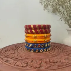 This stack of thread bangles in red, yellow, and blue is a classic festive combination. The set includes different designs, from gota patti work to mirror embellishments.