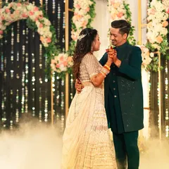 The couple's romantic dance at their Sangeet. Framed by a beautiful floral arch and sparkling lights, they are lost in their own world, creating a picture-perfect memory.