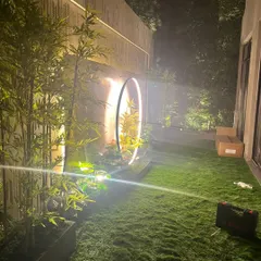 I design green spaces that feel magical, day or night. This residential garden project features my soft artificial turf, complemented by strategic lighting on the surrounding artificial plants and a modern circular sculpture.