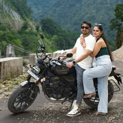 A stylish pose with the motorcycle on a mountain road. This photo captures the cool, adventurous vibe of the couple and their Rishikesh pre-wedding shoot.