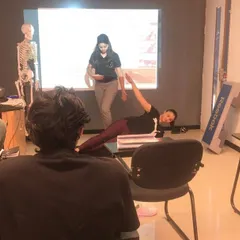 A master trainer demonstrates a side plank variation during a theory class. We use practical demonstrations even in the classroom to explain complex anatomical concepts.
