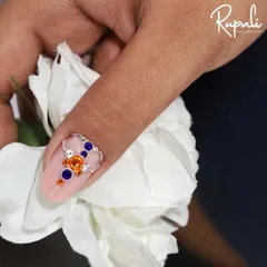 A close-up of a custom jewelry design on a matte pink nail. I used a combination of orange and blue crystals with a delicate silver chain to create this unique, eye-catching piece.
