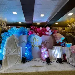 A stage setup for a "Boy or Girl" gender reveal party. I used dramatic blue and pink lighting to highlight the respective balloon colors, creating an exciting and theatrical backdrop for the big announcement.