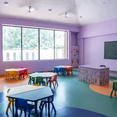 This classroom uses a soothing lavender wall color and features a large window for natural light. The modular, colorful tables can be arranged in various configurations to support different activities, from group work to individual art projects.