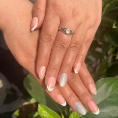 A beautiful French manicure captured in the sunlight. This design features a clean, natural look with white tips and a single silver glitter accent nail for a touch of sparkle.