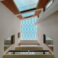 A dramatic upward view of a multi-level courtyard, capped with a geometric skylight that frames the sky. The design pulls light down through the core of the house.