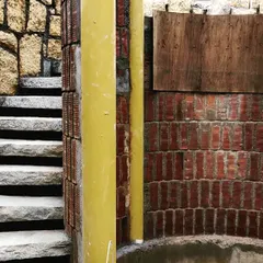 A circular staircase under construction, showing the combination of rough stone steps and a curved brick wall for the lift well. This image reveals the raw structure and the beauty of these fundamental building materials working together.