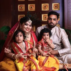 A complete family portrait celebrating Janmashtami. The parents are seated with their two young children, who are delightfully dressed as little Krishnas, showcasing our ability to create beautiful themed shoots for the whole family.