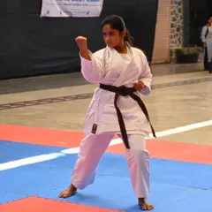 A student demonstrates a powerful stance during her brown belt examination. Her focus and form show she is ready for the next level.