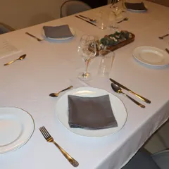 Every detail of the table setting is considered, from the crisp white tablecloth to the polished glassware and neatly folded napkins, ensuring a true fine dining feel.