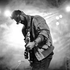 In black and white, the guitarist's posture tells the whole story. It's a candid concert moment showing complete absorption in the sound.