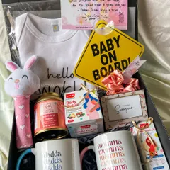 A complete care package for the mom-to-be. This hamper includes body butter, relaxing tea, a 'Baby on Board' sign, a cute rattle, and matching mugs for the new parents.