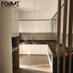 An in-progress view of a U-shaped kitchen with high-gloss white cabinets and a dark countertop. This shows the clean installation and precise fit of our modular units before the final touches are added.