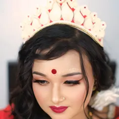 The quintessential Bengali bride. This close-up focuses on the traditional 'mukut' and the intricate 'chandan' designs, capturing the serene beauty of bridal traditions.