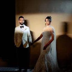 A classic, elegant portrait using dramatic side lighting. The couple holds hands, creating a connection while posing with a sophisticated, high-fashion feel. This style is perfect for couples wanting a glamorous pre-wedding album.