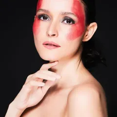Pushing creative boundaries is a passion of mine. For this conceptual shoot, I used bold red face paint to create a graphic, monochromatic look, demonstrating my skills in artistic and avant-garde makeup for high-fashion editorials.