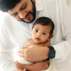 A proud father holding his newborn, who looks directly at the camera. Capturing these moments of eye contact is so special in the early days.