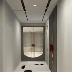 A view down a corridor with minimalist white marble flooring featuring black inlay details, leading to a modern door with fluted glass panels.