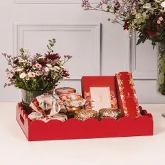 Our Diwali hampers are designed to be a feast for the eyes and the palate. This vibrant red tray is filled with our finest floral-wrapped desserts, jars of sweets, and elegant candle holders.