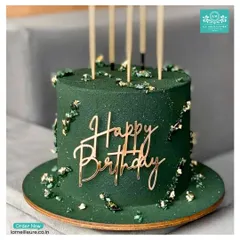 This sophisticated birthday cake features a deep forest green frosting, flecks of edible gold leaf, and a modern, gold acrylic 'Happy Birthday' topper. It's a perfect example of a chic and elegant design for an adult celebration.