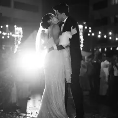 A classic black and white shot of the first dance under the stars. The dramatic backlighting and the couple's kiss create a cinematic moment, capturing the magic of their first steps as husband and wife.