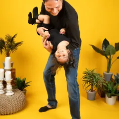 A playful moment between a father and his little girl. The bright yellow background makes the fun and energy of this photo pop.