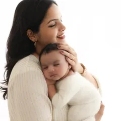 A mother's gentle hold. This portrait focuses on the serene bond between mother and child, capturing the baby's peaceful sleep and the mother's loving gaze.