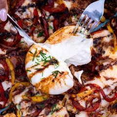 A close-up of a burrata pizza, showing the creamy cheese being cut into. The macro perspective makes the viewer feel like they are right there, ready to take a bite.