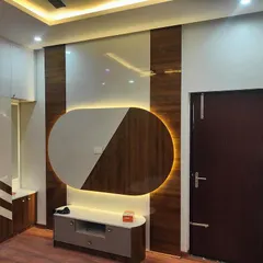 A bedroom featuring a unique TV unit with an oval backlit panel and a chevron-patterned wardrobe. This custom design demonstrates our ability to create artistic and functional statement pieces for any room.