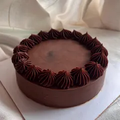 A classic 6-inch eggless chocolate cake. It's a rich chocolate sponge covered entirely in smooth, dark chocolate ganache with a simple piped border.