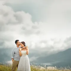 An intimate embrace against a backdrop of clouds resting on the mountains. I use my 85mm lens to create this soft, compressed background, making the couple the clear, emotional focus of this romantic portrait.