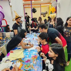 A table full of kids and parents working together on 'Ghostly Glow Jars'. I love providing activities that the whole family can enjoy side by side.