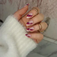This elegant design reimagines the French manicure with abstract swirls of deep magenta and crisp white, highlighted by a delicate gold line. It's a sophisticated and artistic style for any nail length.