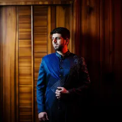 A dramatic, low-light portrait of the groom in his stylish reception sherwani, using shadows to create a powerful image.