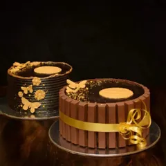 Two of my popular chocolate cake designs side-by-side. On the left, a minimalist design with gold butterflies, and on the right, the classic KitKat cake. Both were made during a 36-hour power cut.