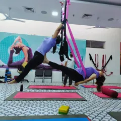 Here, two students perform a beautiful, symmetrical partner pose using the aerial silk. One acts as the base while the other is suspended, showcasing the strength and grace that can be developed through this practice.
