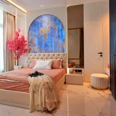 For this young client's bedroom, we created a sanctuary that reflects her personality. The design centers around a stunning blue stone arch, complemented by soft peach and white tones, while the deep blue fluted wardrobes add a touch of modern sophistication.
