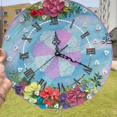 A custom 12-inch wall clock designed with a blue and pink theme to match a client's room. The pinwheel-style textured center and sculpted floral arrangements make this a truly personal and pretty piece.