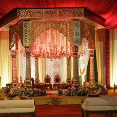 This mandap was designed as a royal court, featuring intricately carved gold pillars and a jharokha-style canopy with a breathtaking chandelier of crystal strings and red roses.