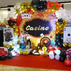 The main photo backdrop for the casino party. It includes a custom 'Casino' sign, a glittering background, and themed balloon arrangements in gold, black, red, and white to create a perfect photo opportunity.