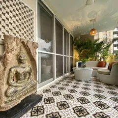 A wider view of the Palm Springs balcony, showing how the patterned floor tiles extend across the space. The carved Buddha panel adds a spiritual and artistic touch, making the balcony feel like a personal retreat.