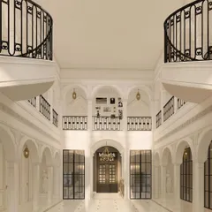 This symmetrical view of the neo-classical lobby showcases its perfect balance and proportion. The design features twin curved balconies and a series of grand archways, creating a powerful visual axis that draws guests into the heart of the building.