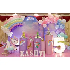 A magical unicorn-themed 5th birthday party featuring a rainbow balloon arch, a dreamy cloud backdrop, and a large light-up number '5'.