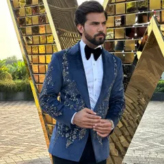 Make an unforgettable entrance with our hand-embroidered Nacre Tuxedo. The deep navy blue velvet provides a rich canvas for the intricate floral embroidery, creating a masterpiece of formal wear for weddings and galas.