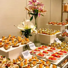 A vibrant and elegant display of our gourmet canapés, featuring a variety of textures and flavours like smoked salmon crostini and tomato tarts. This spread, accented with fresh lilies, showcases our dedication to artisanal food presentation.